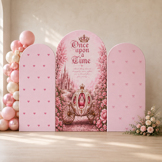 A pink princess-themed party backdrop set featuring three arched panels: a central panel with 'Once upon a Time' text, a carriage, and a castle, flanked by two plain pink panels with heart and bow prints. The set is styled with pink and white balloons on the left and a floral arrangement on the right against a beige wall.